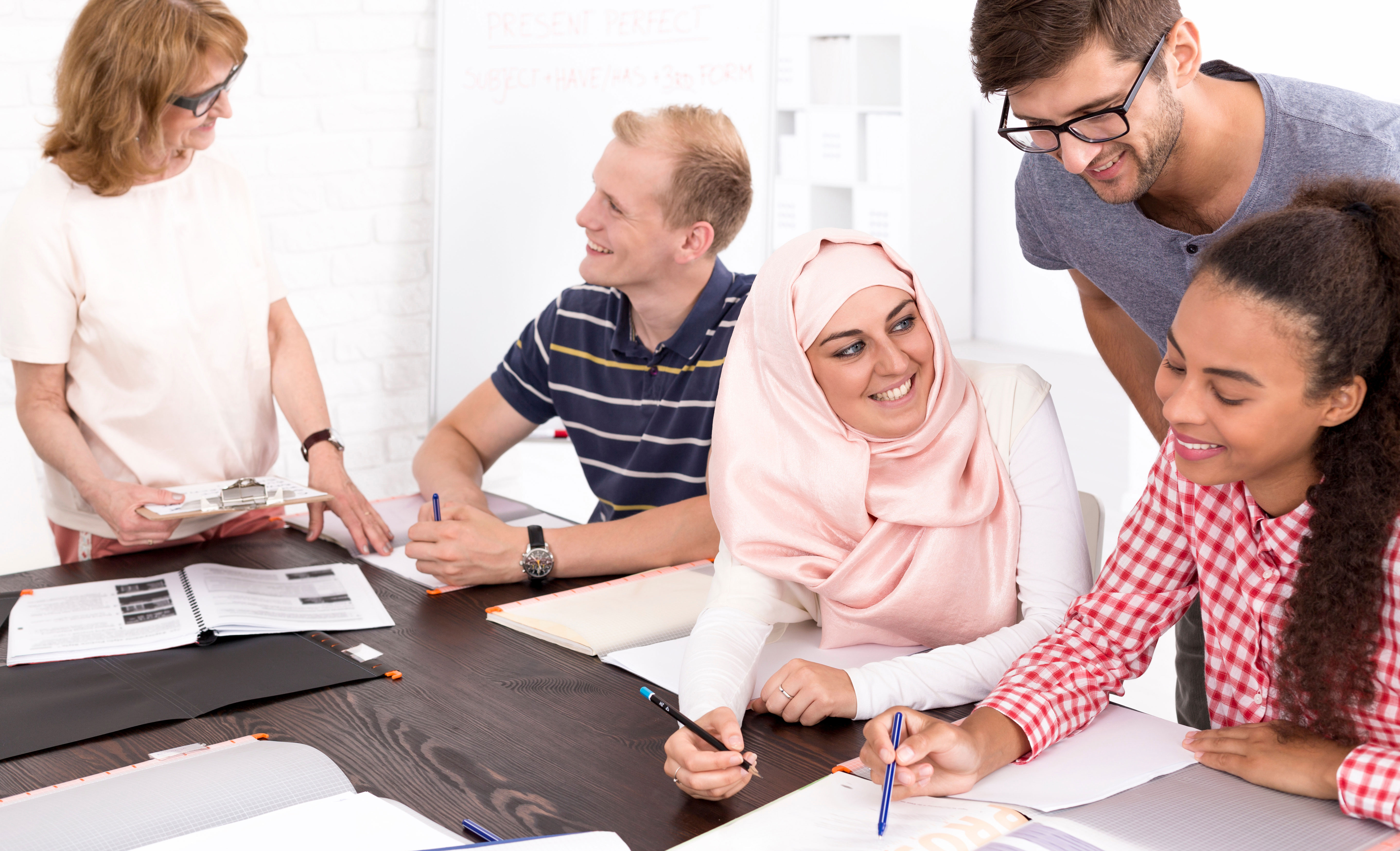 erwachsene mit unterschiedlichen ethnizitäten am tisch versammelt, die sich weiterbilden erwachsene mit unterschiedlichen ethnizitäten am tisch versammelt, die sich weiterbilden